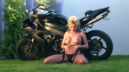 Busty blonde teases on a motorcycle in nylon